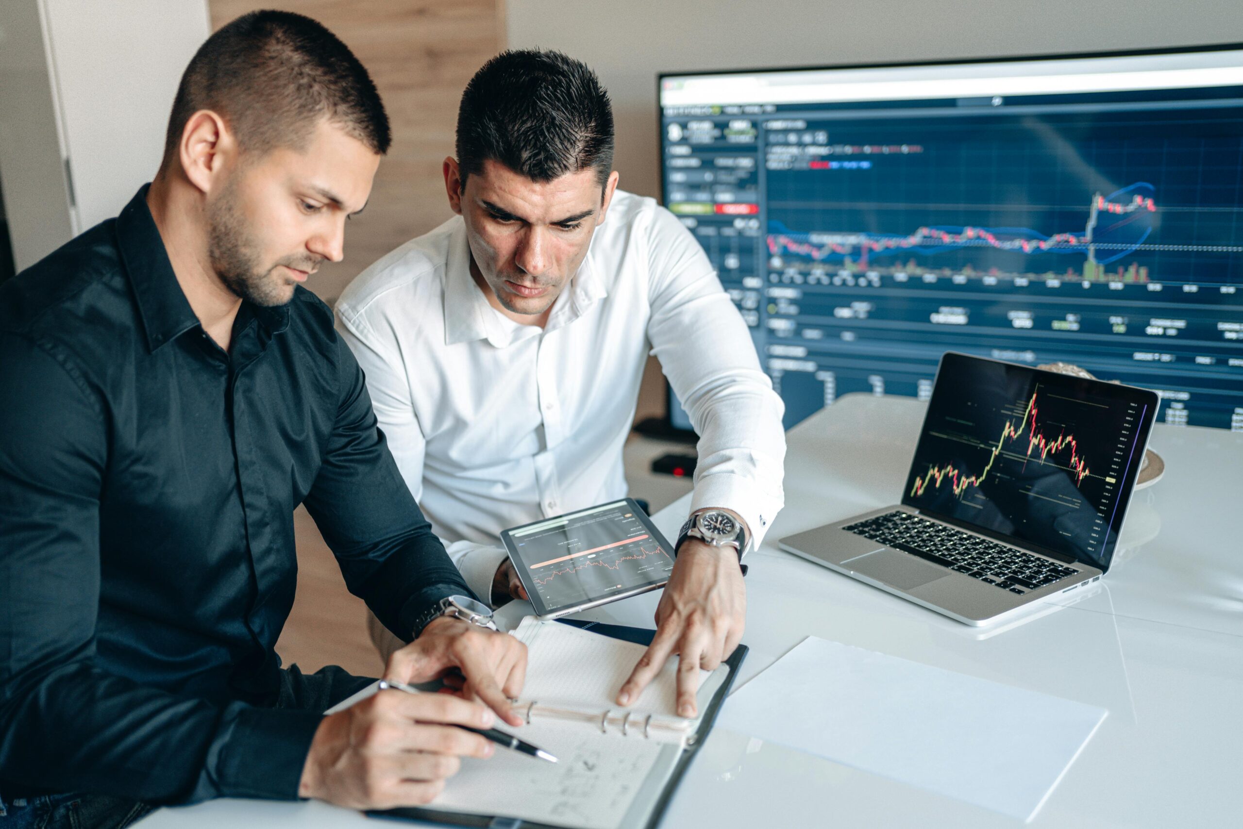 professional men working together on charts near a laptop and computer