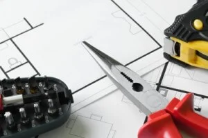 Pliers and a tape measure lying on top of architectural blueprints.