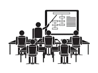Silhouette of a teacher pointing at a whiteboard, presenting to a class of students.