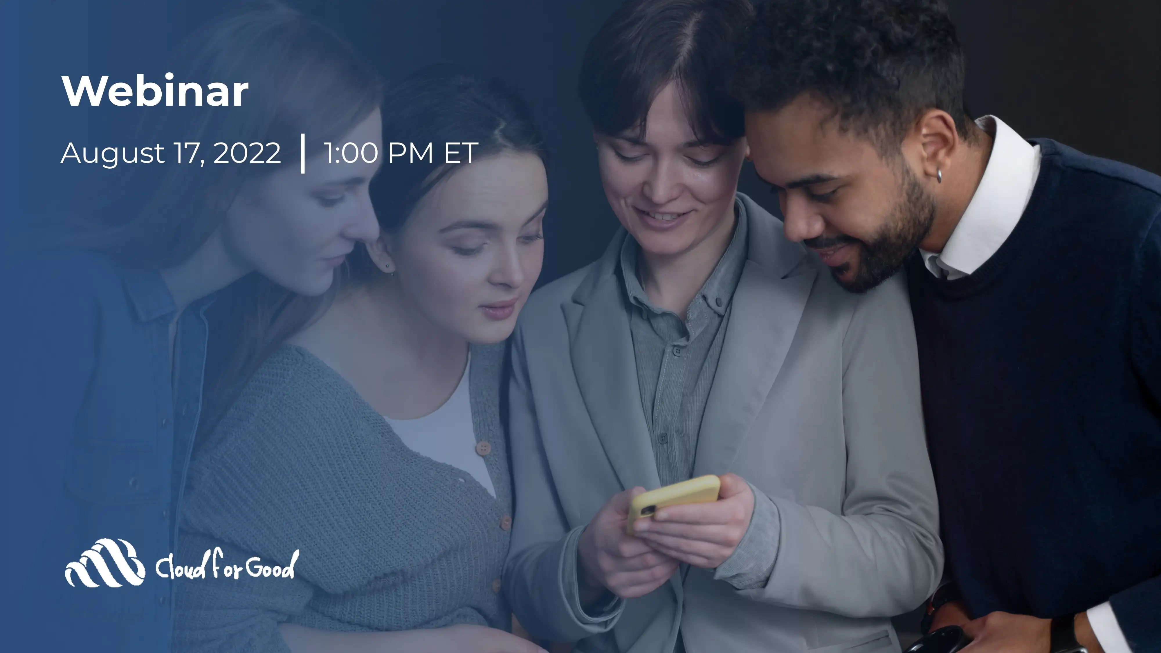 Four young professionals gathered around a smartphone, smiling