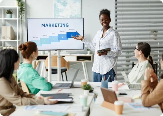 Presenter explaining a marketing slide to a team seated around a conference table