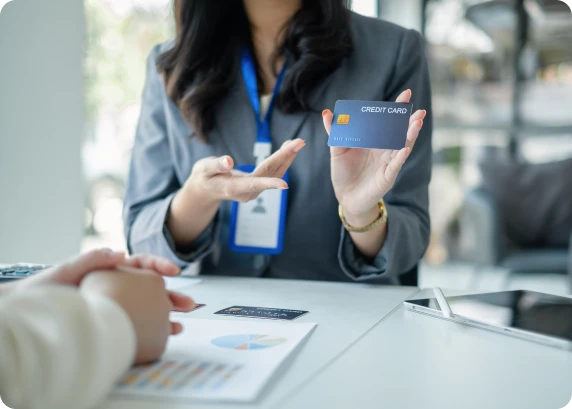 Credit union representative presenting a credit card to a member during a financial consultation