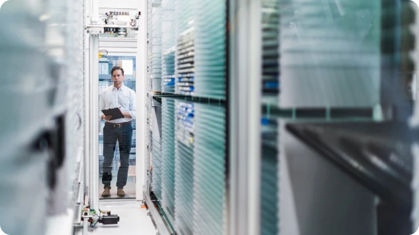 Professional standing between server racks in a data center holding a tablet