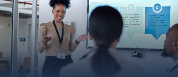 Presenter speaking to seated attendees in front of a presentation screen