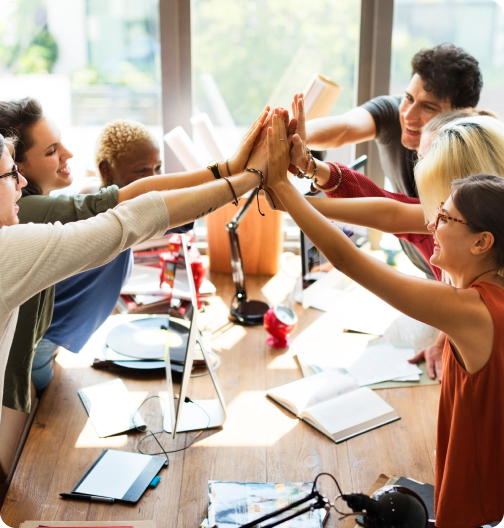 Diverse team members celebrating together in an office meeting with a group high-five