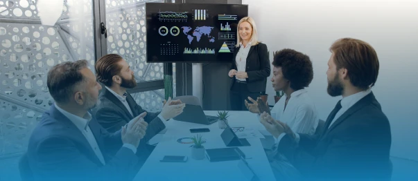 Business team applauding a presenter beside an analytics dashboard in a meeting room